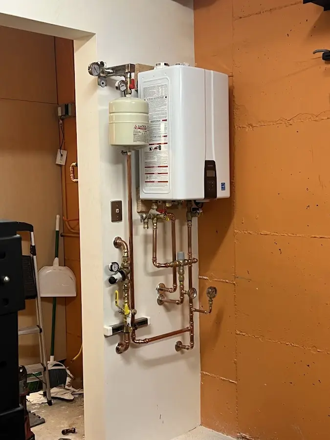 Plumbing technician inspecting water heater connections in Charlestown